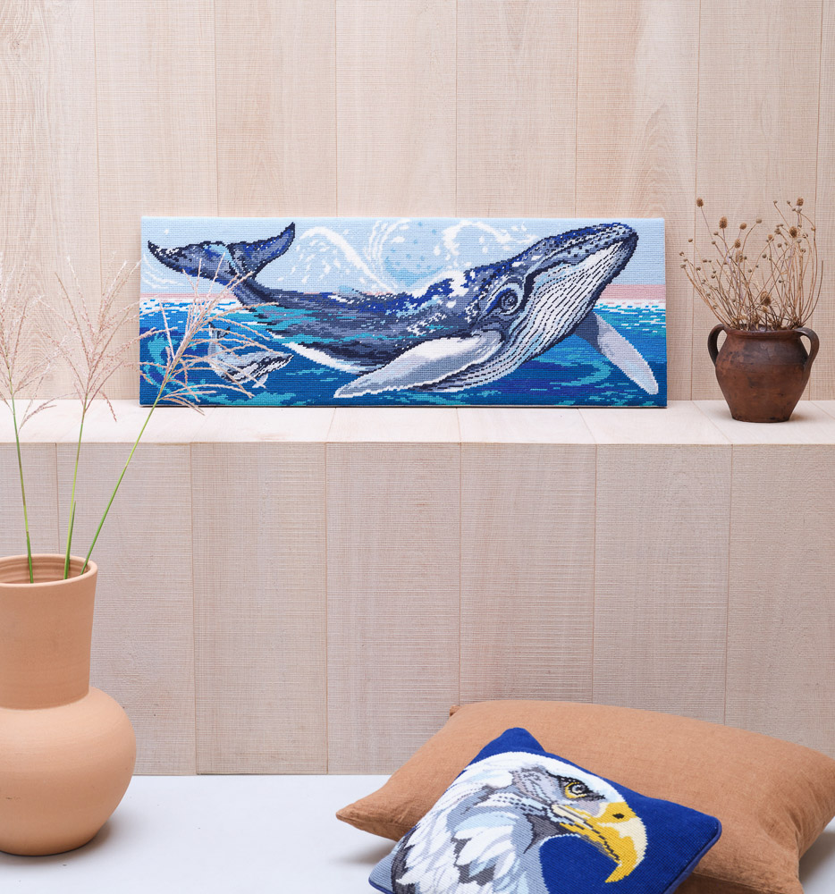 Whale panel sitting on a shelf attached to a wood panelled wall, with potted flowers as decorations